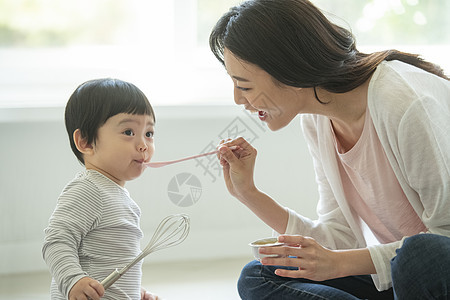 妈妈陪小朋友坐在客厅地毯上吃饭图片