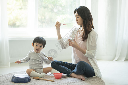 妈妈陪小朋友坐在客厅地毯上吃饭图片