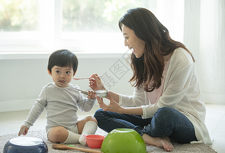 妈妈陪小朋友坐在客厅地毯上吃饭图片