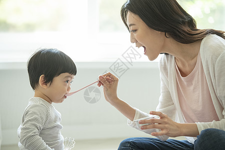 妈妈陪小朋友坐在客厅地毯上吃饭图片