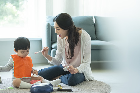 妈妈陪小朋友在客厅地毯上吃饭图片