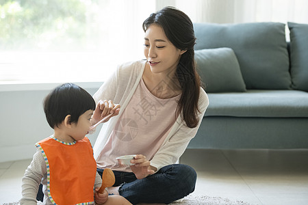 妈妈陪小朋友在客厅地毯上吃饭图片