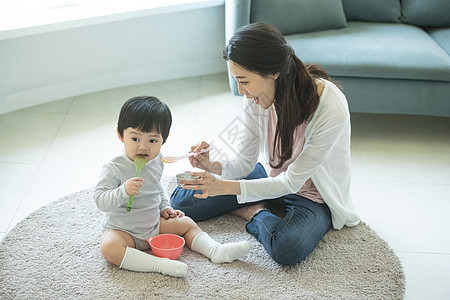 母亲拿着小勺喂孩子背景图片