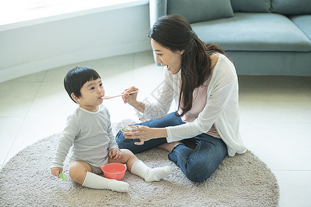 母亲拿着小勺喂孩子图片