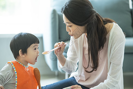 年轻母亲拿着勺子喂孩子图片