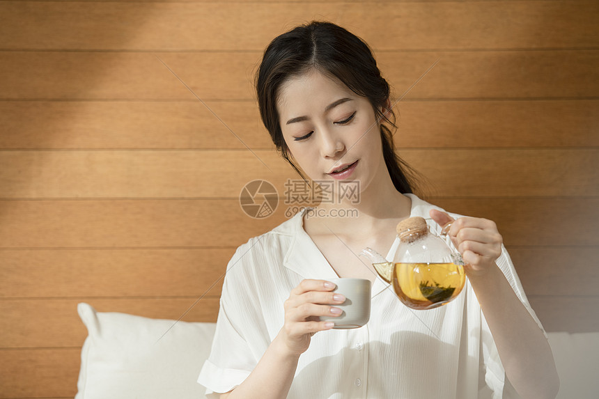 拿着茶壶倒茶的青年女子图片