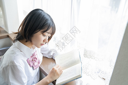 坐在窗边阅读的少女图片