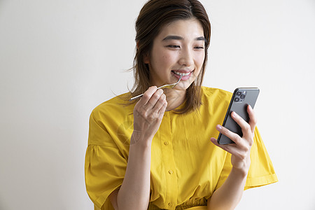 吃饭看着手机的年轻女子图片素材