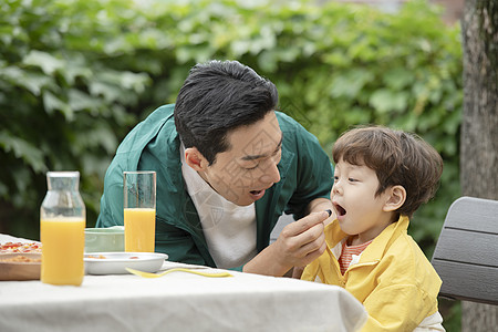 户外野餐喂孩子吃水果的父亲图片