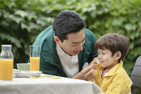户外野餐喂孩子吃水果的父亲图片