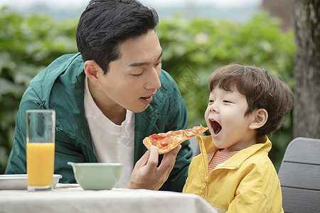 户外野餐喂孩子吃披萨的父亲图片