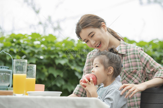 女儿坐在妈妈边上吃苹果图片