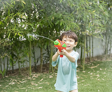 户外庭院玩水枪的小男孩图片素材
