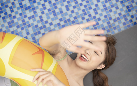 夏日泳池边拿着游泳圈的年轻女子图片