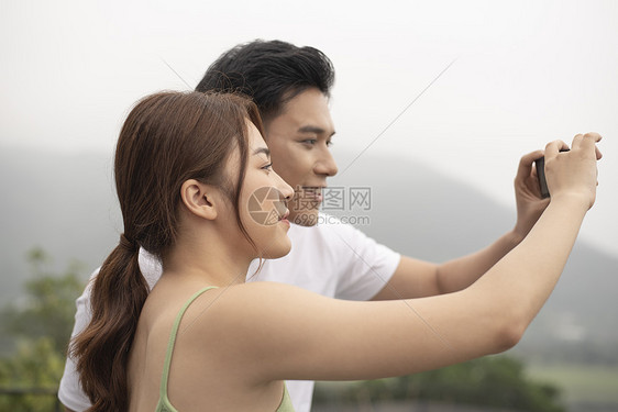 情侣旅游拿着相机拍风景图片