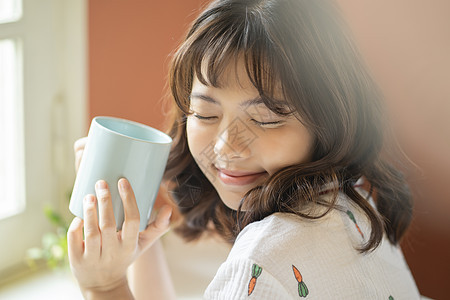 拿着咖啡微笑的居家女子图片