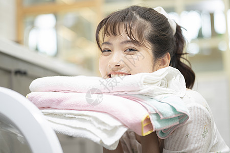 居家做家务抱着毛巾的年轻女子图片