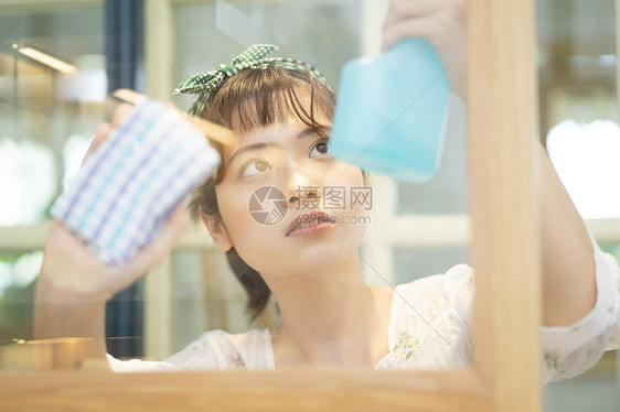 做家务清洁玻璃的年轻女子图片