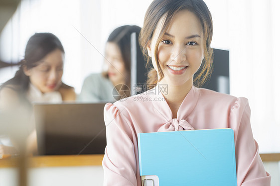抱着文件微笑的职场女性图片