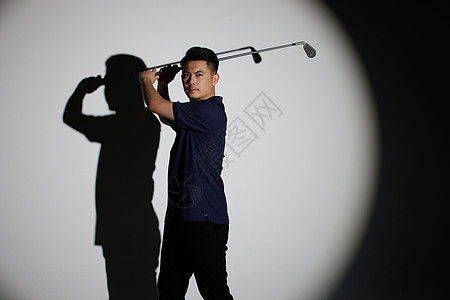 聚光灯下的男运动员打高尔夫球背景图片
