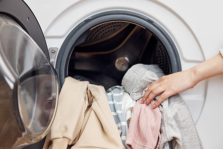 家用中央空调把脏衣物放进滚筒洗衣机特写背景