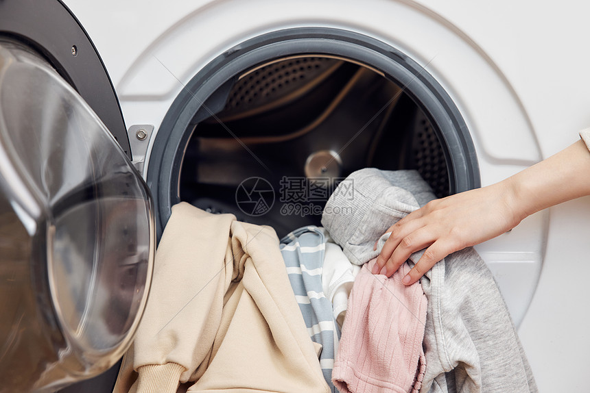 把脏衣物放进滚筒洗衣机特写图片