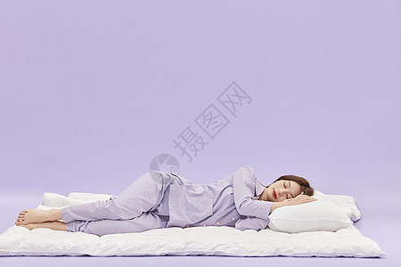 身着睡衣的年轻少女躺在被子上睡觉图片