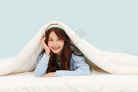 身着睡衣的年轻少女躲在被窝里图片素材