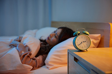 国际留学居家女性卧室睡觉和床头柜上的闹钟背景