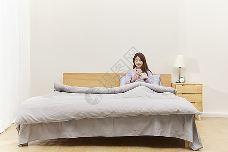 居家床上玩手机的女生图片