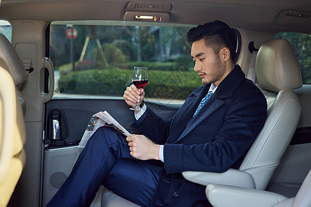 商务男士车内喝红酒看报纸图片