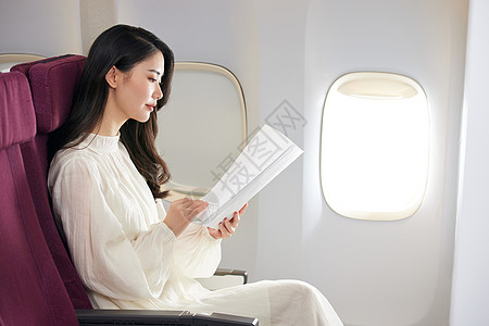 商务旅行年轻美女飞机上翻阅文件背景