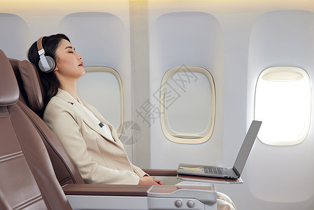 年轻女性飞机上听音乐休息图片