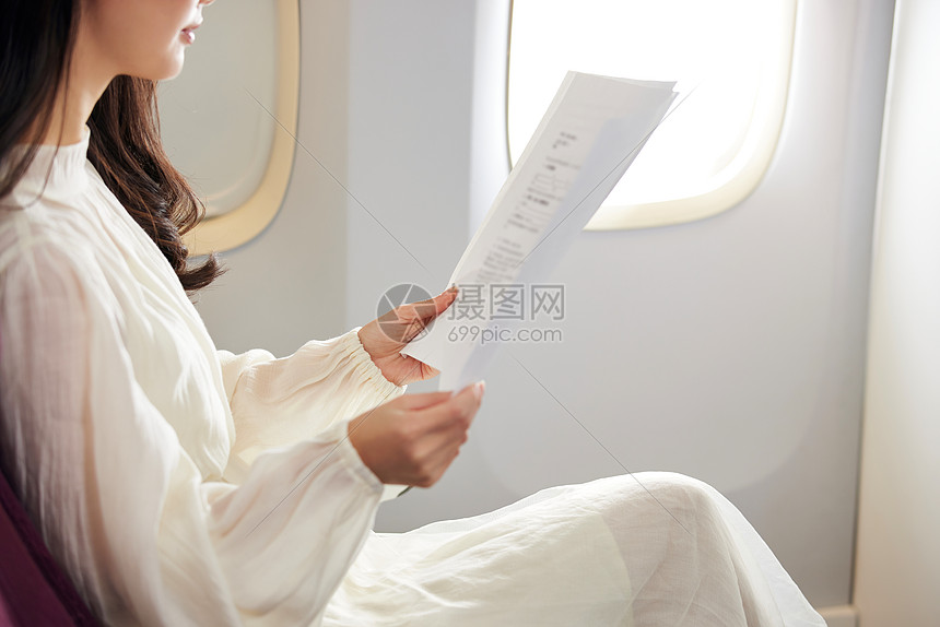 年轻女性乘坐飞机查看文件特写图片