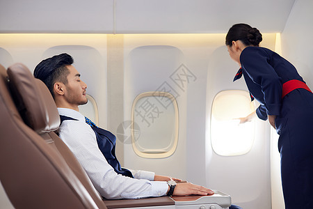 空姐为熟睡的乘客关闭遮光板图片