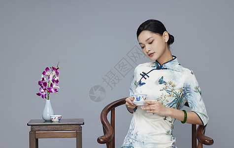 年轻旗袍女性端坐品茶图片