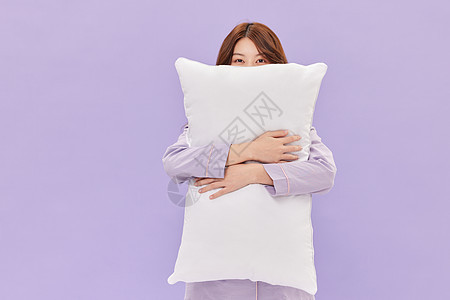 身着睡衣的年轻少女抱着枕头背景图片