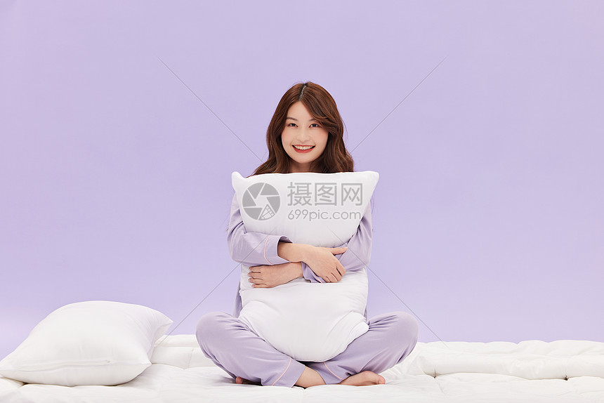 睡衣少女坐在被子上开心微笑图片