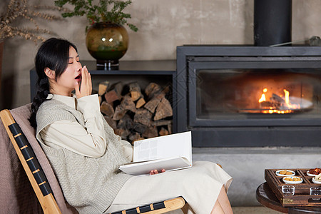 冬天坐在火炉边看书犯困的女性图片