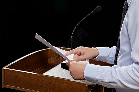 舞台幕布讲台上拿着演讲稿发言的商务男士特写背景