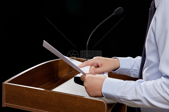 讲台上拿着演讲稿发言的商务男士特写图片