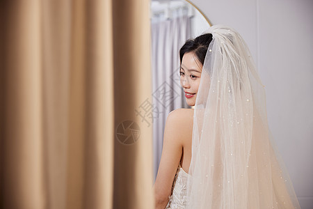 结婚礼服美女穿着婚纱站在镜子前背景