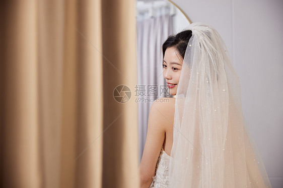 美女穿着婚纱站在镜子前图片