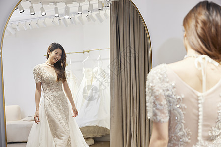 美女穿着婚纱站在镜子前露出喜悦的表情图片