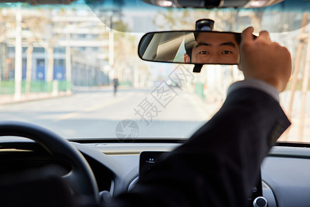 神州专车男性司机驾车调整后视镜角度背景