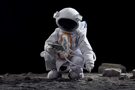 宇航员手拿平板电脑蹲在地上图片