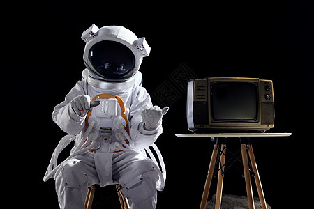 边上上的椅子宇航员坐在椅子上边上放着电视机背景