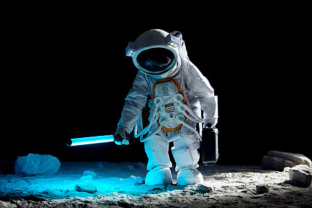 宇航员手持探照设备站在月球表面上图片