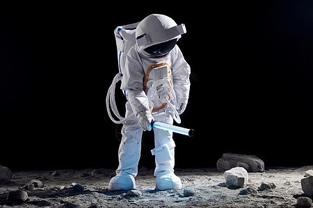 宇航员手持探照设备站在月球表面上图片
