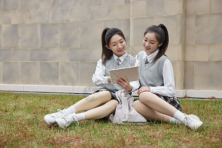 坐在草地上看平板的美女同学图片